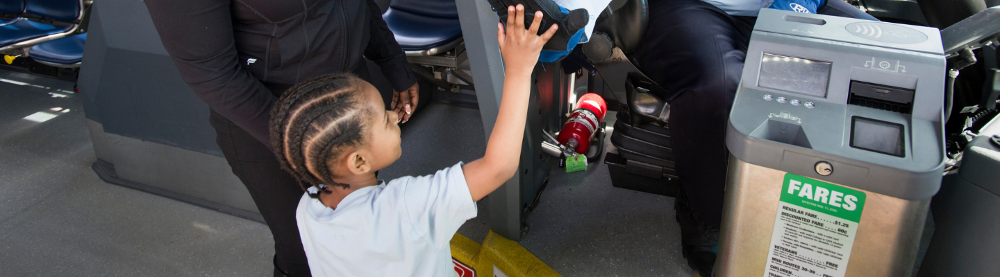A child high-fiving a driver next to a CATA farebox