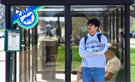 Person waiting at CATA bus stop and shelter