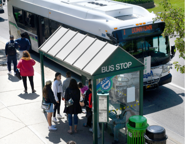 People waiting at a bus stop for a CATA bus